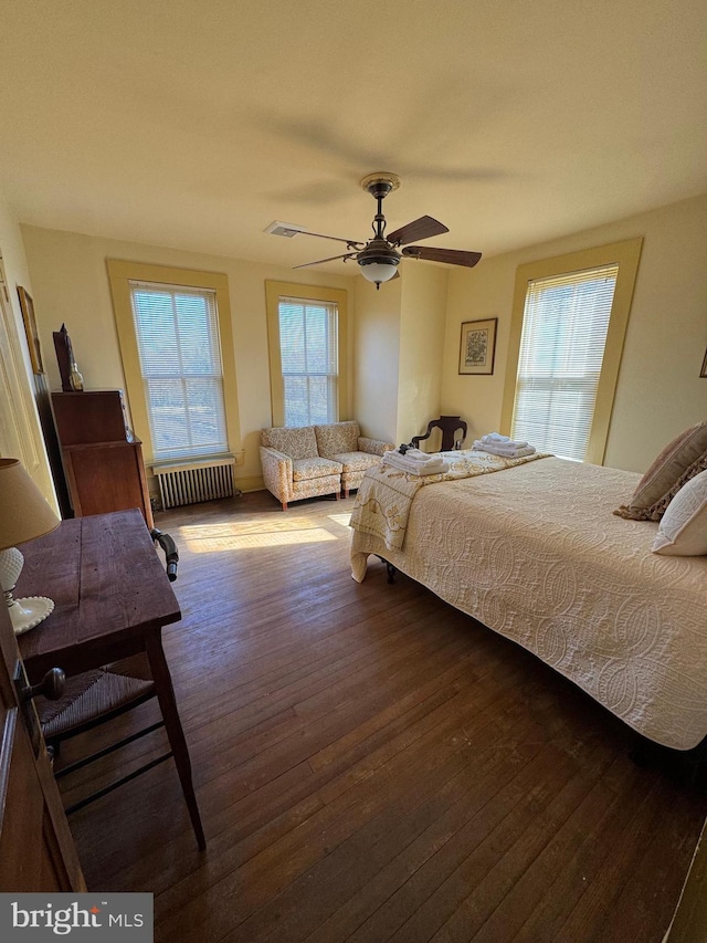 bedroom featuring dark wood-style floors, ceiling fan, visible vents, and radiator