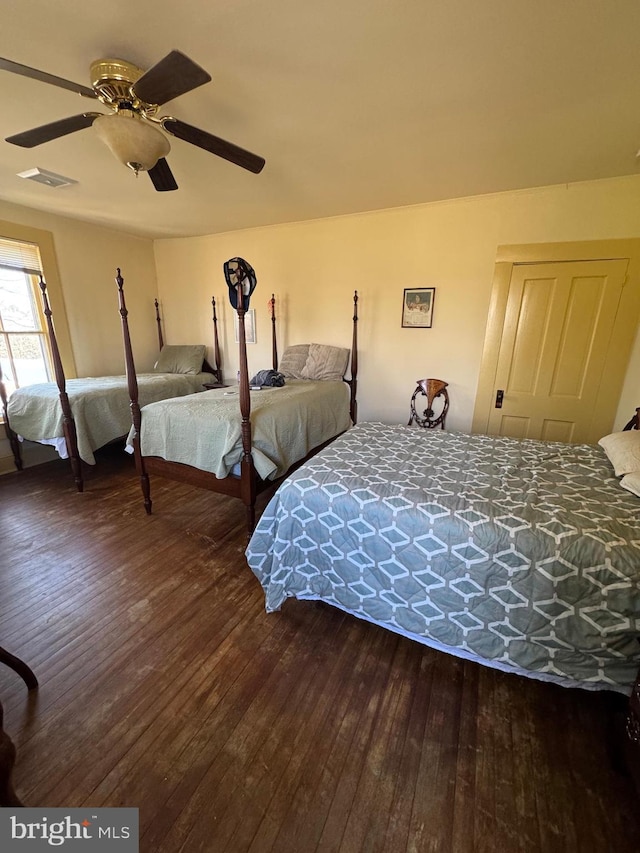 bedroom with hardwood / wood-style floors, visible vents, and a ceiling fan