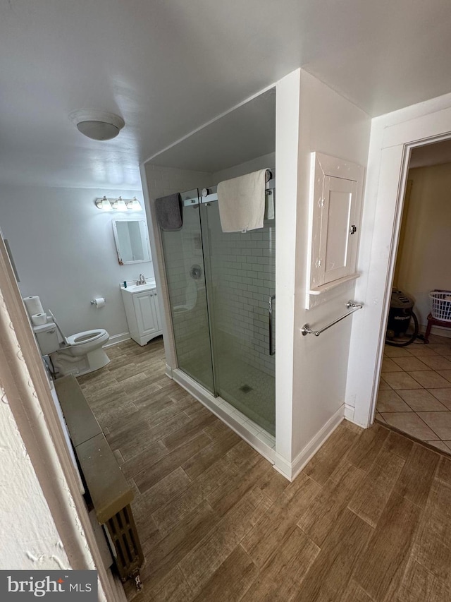 full bath featuring vanity, a shower stall, toilet, and wood finished floors