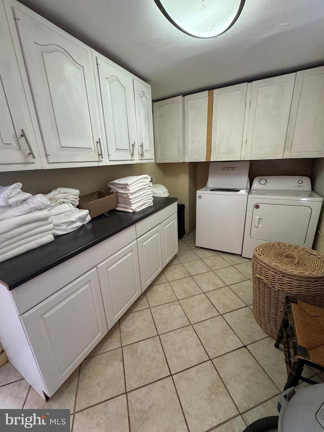 clothes washing area featuring washing machine and dryer, cabinet space, and light tile patterned floors