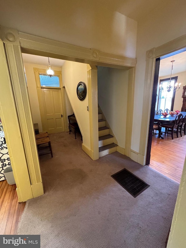 below grade area featuring a chandelier, carpet flooring, stairway, and wood finished floors