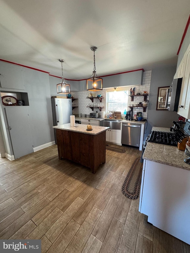 kitchen with white cabinets, a center island, stainless steel appliances, wood finish floors, and a sink