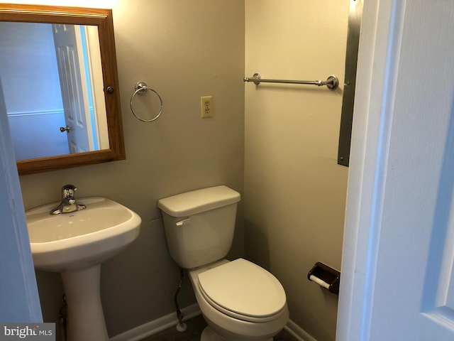 half bath with a sink, toilet, and baseboards