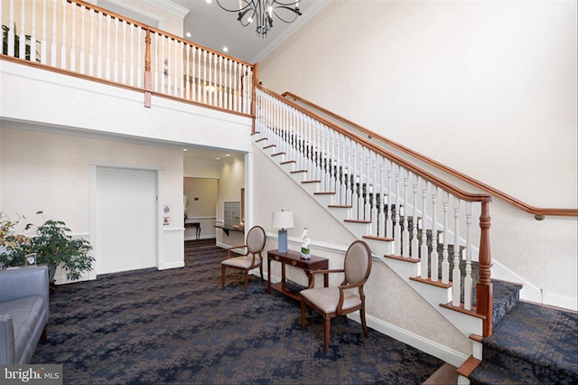 stairs with carpet floors, a towering ceiling, ornamental molding, a chandelier, and baseboards