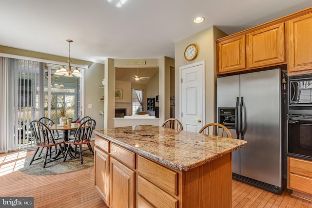 kitchen featuring a kitchen island, black appliances, a fireplace, and a healthy amount of sunlight