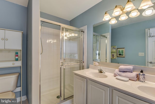 bathroom featuring double vanity, a shower stall, toilet, and a sink