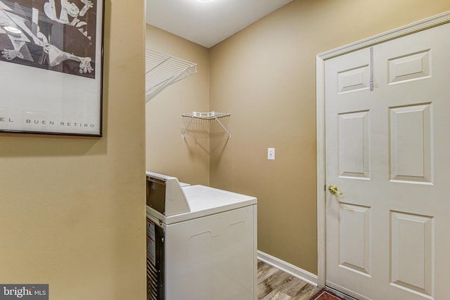 clothes washing area featuring baseboards, washer / clothes dryer, and wood finished floors