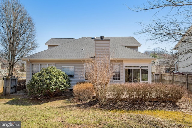 rear view of property featuring fence, roof with shingles, a lawn, a chimney, and a sunroom