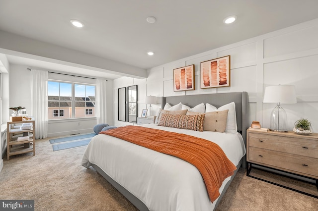 carpeted bedroom with recessed lighting and a decorative wall