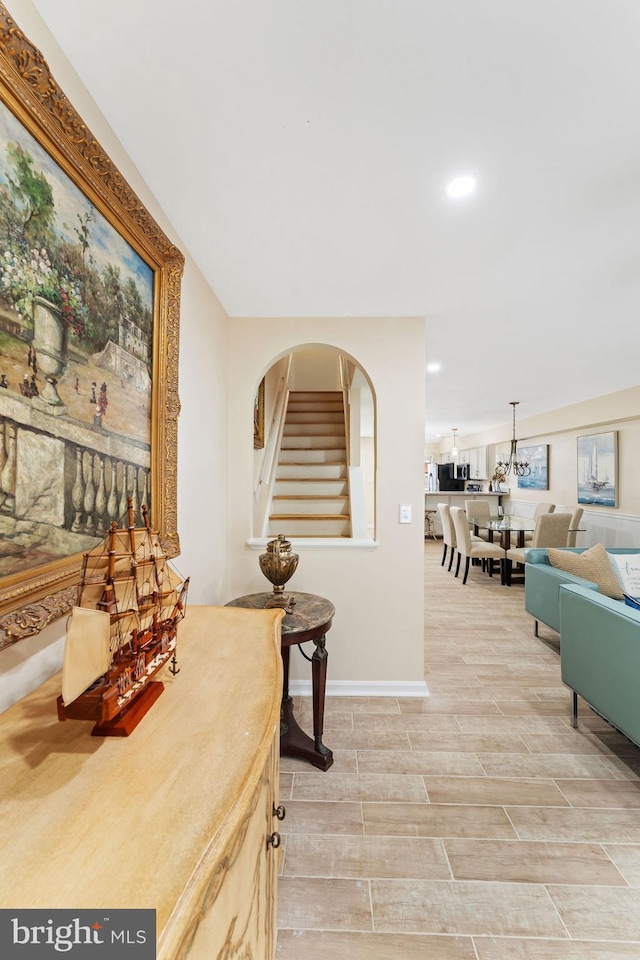 hallway featuring recessed lighting, baseboards, stairs, wood tiled floor, and an inviting chandelier