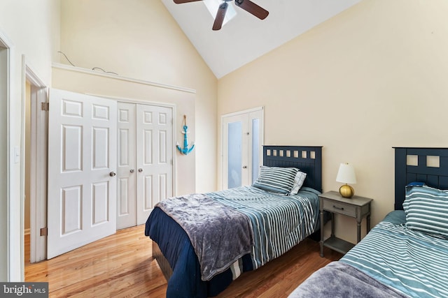 bedroom with a ceiling fan, a closet, high vaulted ceiling, and wood finished floors