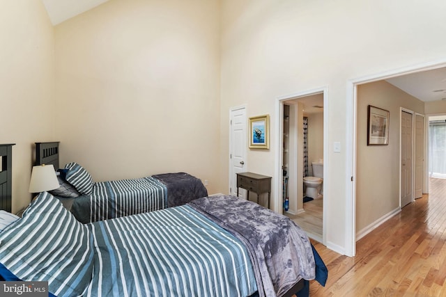 bedroom with light wood-style floors, baseboards, and connected bathroom