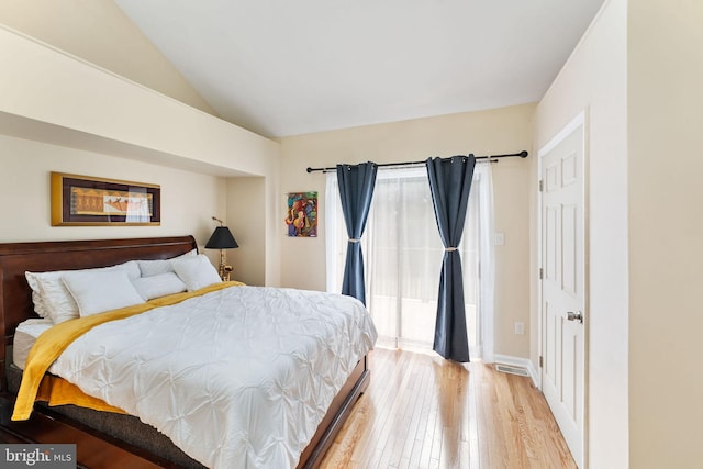 bedroom with access to exterior, light wood-type flooring, and vaulted ceiling