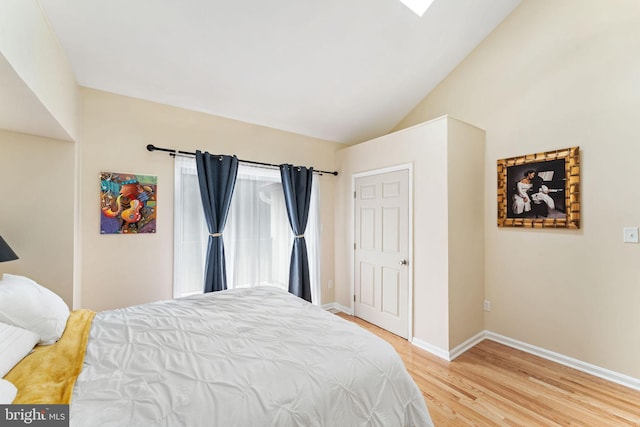 bedroom featuring light wood-type flooring, lofted ceiling, and baseboards