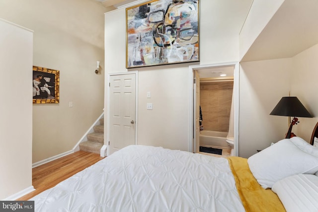 bedroom featuring connected bathroom, baseboards, and wood finished floors