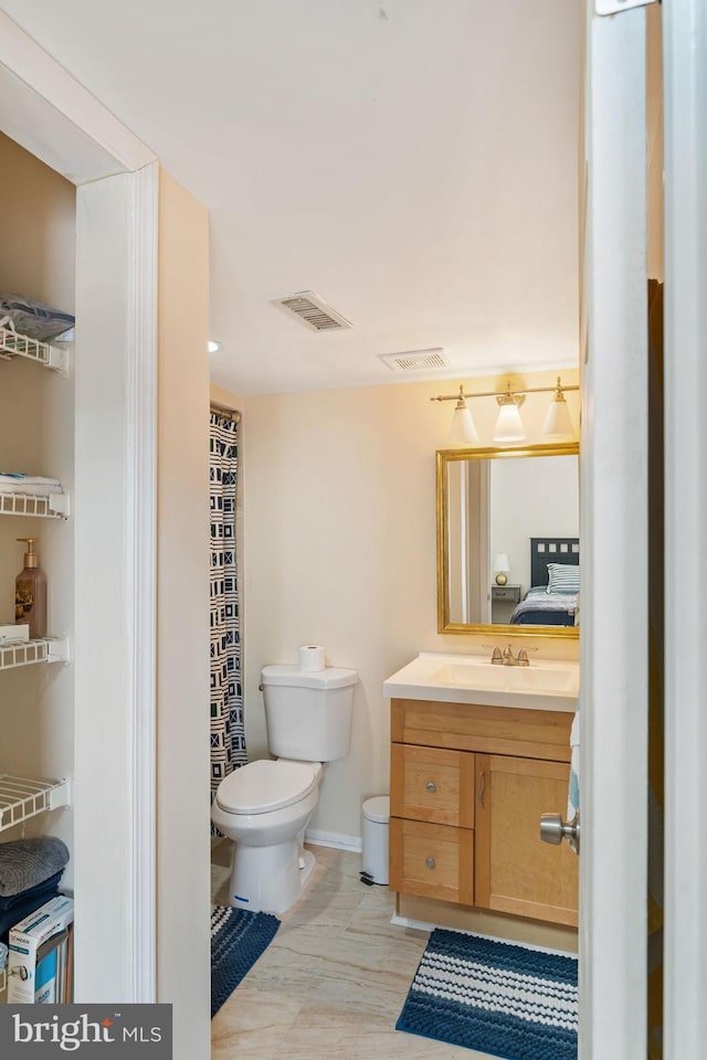 bathroom with toilet, visible vents, wood finished floors, and vanity