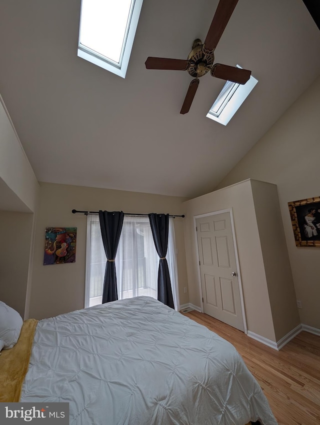 bedroom featuring high vaulted ceiling, a skylight, baseboards, and light wood finished floors