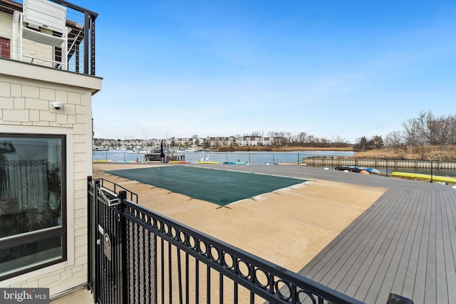 view of swimming pool with a water view and fence