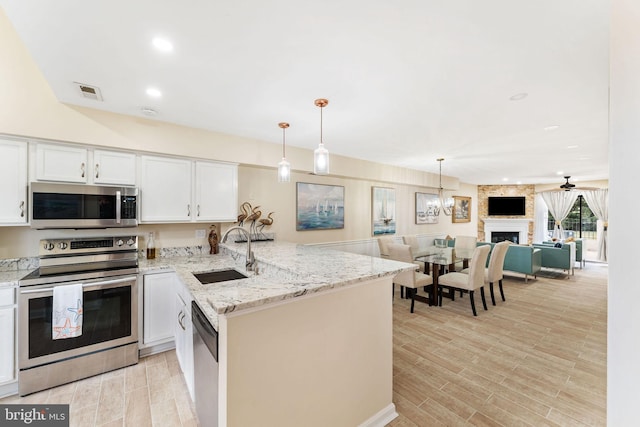 kitchen with stainless steel appliances, a peninsula, a sink, visible vents, and open floor plan