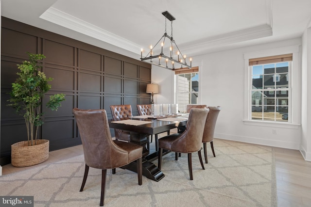 dining area with a wealth of natural light, a raised ceiling, and ornamental molding