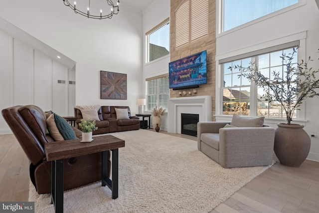 living area with a healthy amount of sunlight, a fireplace, crown molding, and wood finished floors