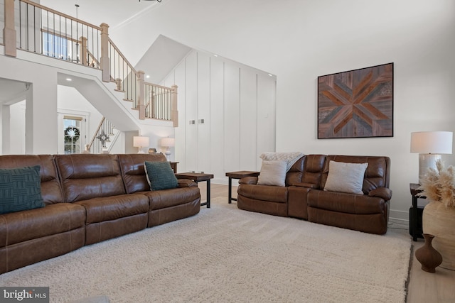 living area with baseboards, a towering ceiling, and stairs