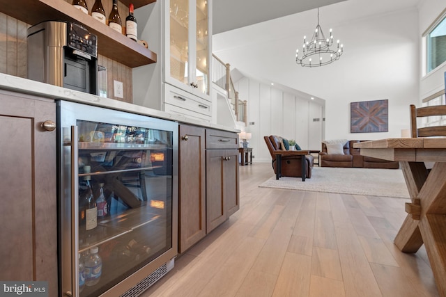 interior space featuring light wood-style flooring, a notable chandelier, and beverage cooler