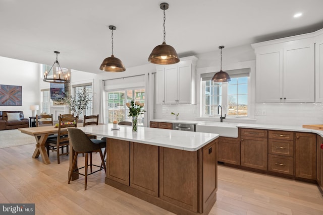 kitchen featuring a sink, tasteful backsplash, light wood-style flooring, and a center island