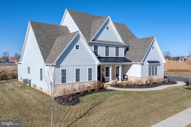 view of front facade featuring metal roof, roof with shingles, a front yard, and a standing seam roof