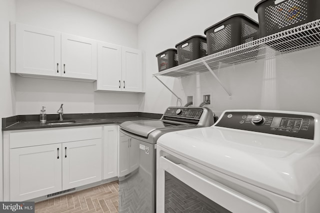 washroom with a sink, cabinet space, visible vents, and washing machine and clothes dryer