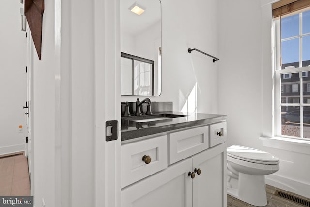 bathroom featuring visible vents, toilet, vanity, and wood finish floors