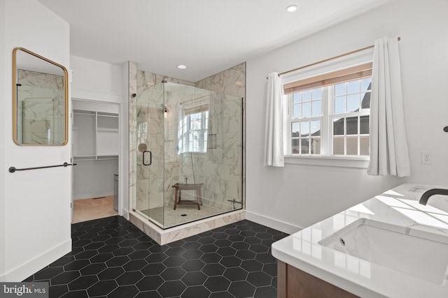 bathroom with a stall shower, a sink, recessed lighting, baseboards, and a spacious closet