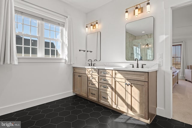 ensuite bathroom with a shower stall, a healthy amount of sunlight, and a sink