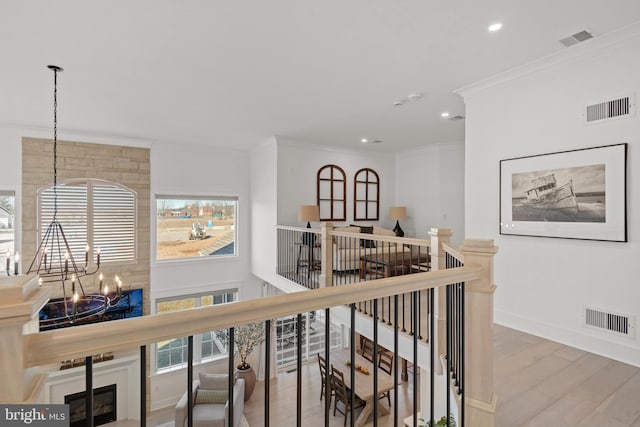 hallway with an inviting chandelier, wood finished floors, an upstairs landing, and visible vents