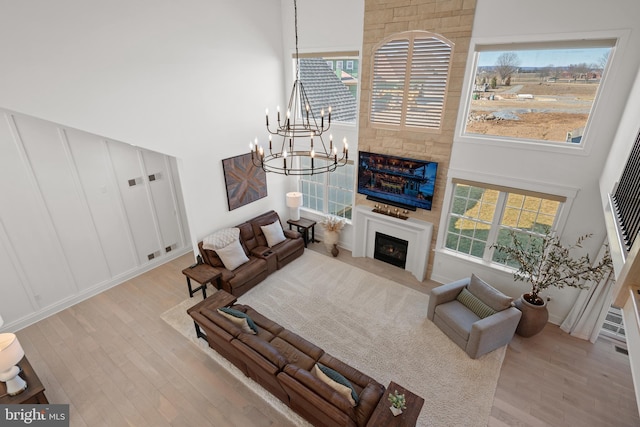 living area with a high ceiling, wood finished floors, a fireplace, and a decorative wall