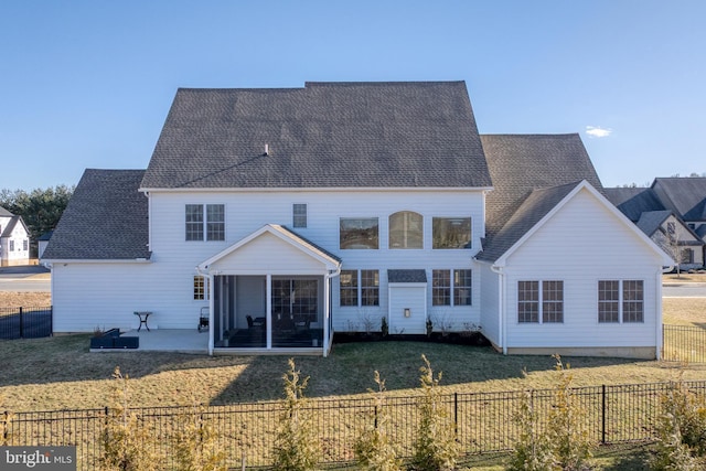 rear view of house with a patio, a yard, a fenced backyard, a sunroom, and a shingled roof