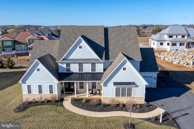 shingle-style home with a standing seam roof, stone siding, a shingled roof, and metal roof