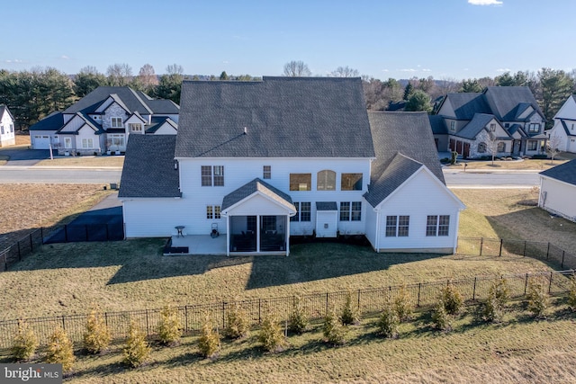 back of property featuring a lawn, a residential view, a fenced backyard, and a shingled roof