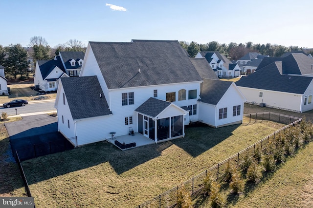 rear view of house featuring a patio, a fenced backyard, a sunroom, a shingled roof, and a lawn