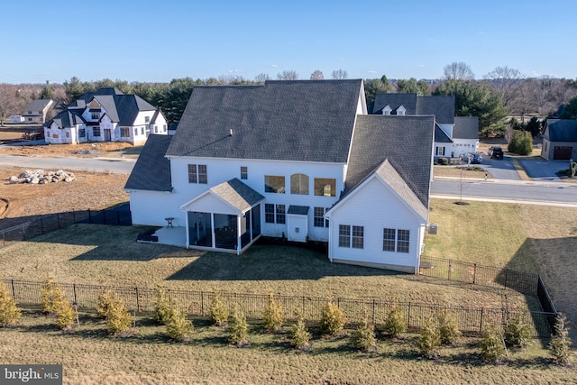 back of property with a sunroom, a lawn, a fenced backyard, and a shingled roof