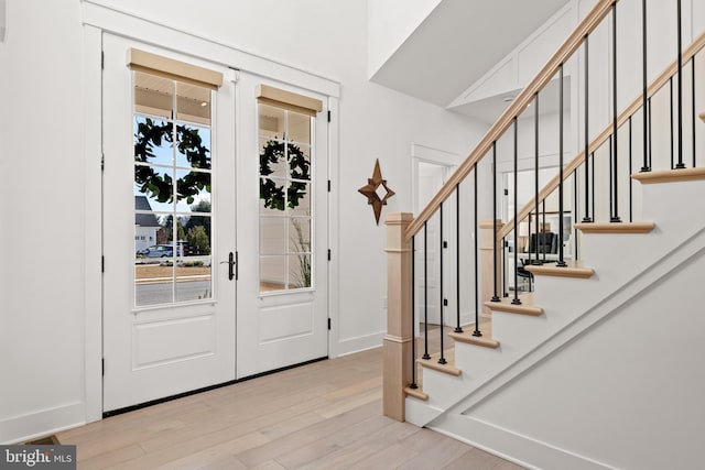 foyer entrance with wood finished floors, stairway, french doors, and baseboards