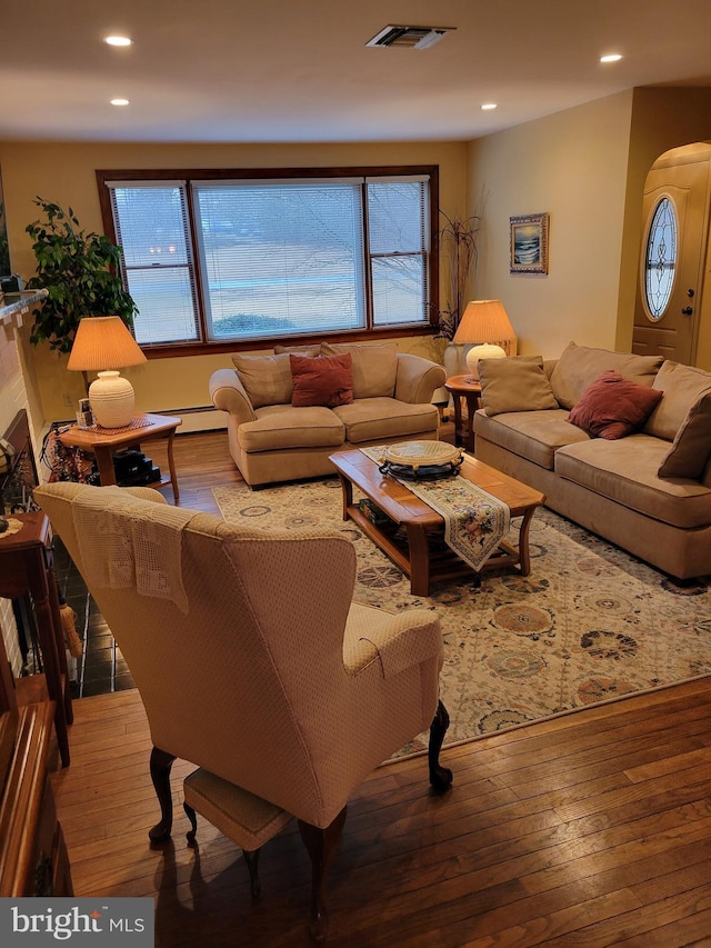 living room featuring hardwood / wood-style flooring, visible vents, arched walkways, and recessed lighting