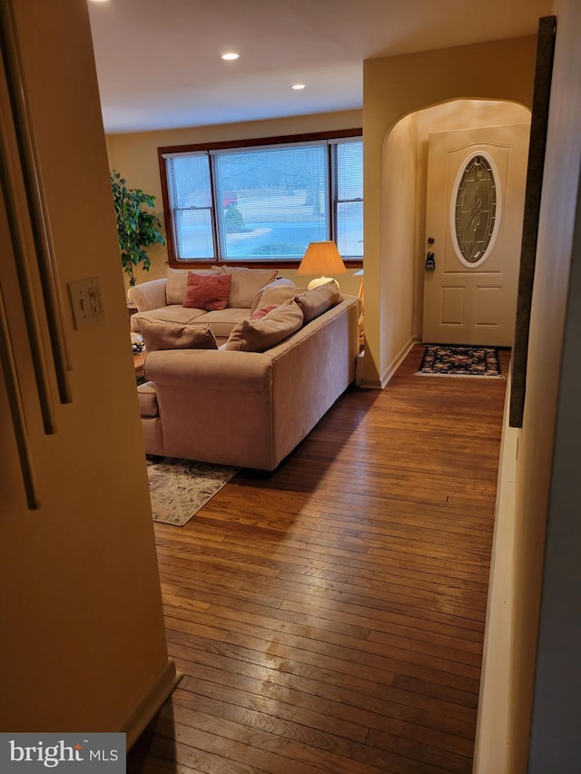 living area with arched walkways, hardwood / wood-style floors, and recessed lighting