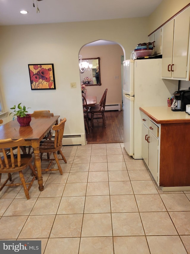 kitchen with light tile patterned floors, a baseboard radiator, arched walkways, and light countertops