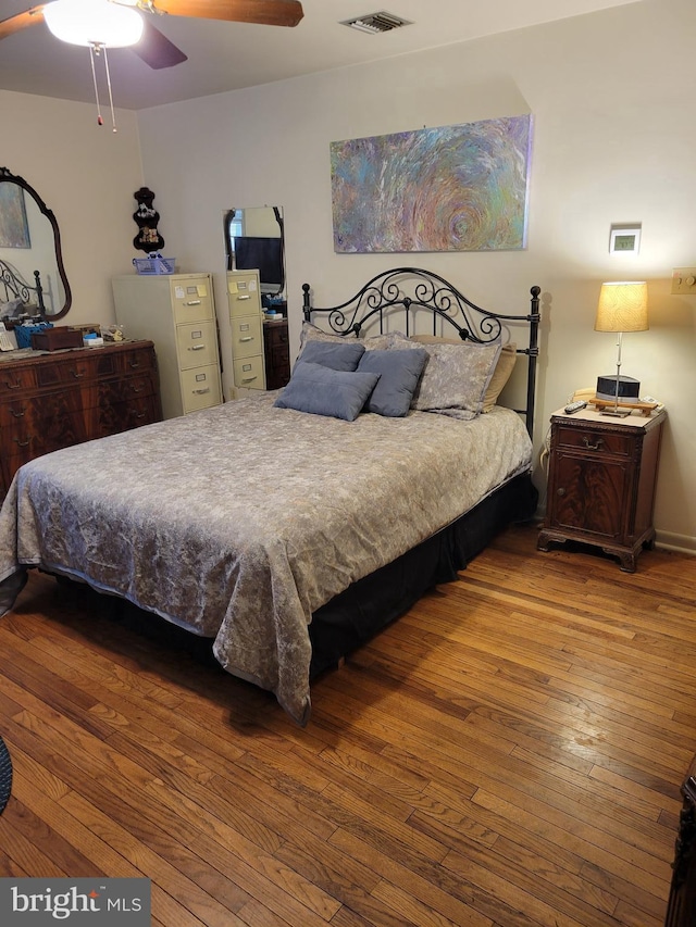 bedroom with a ceiling fan, visible vents, and hardwood / wood-style floors