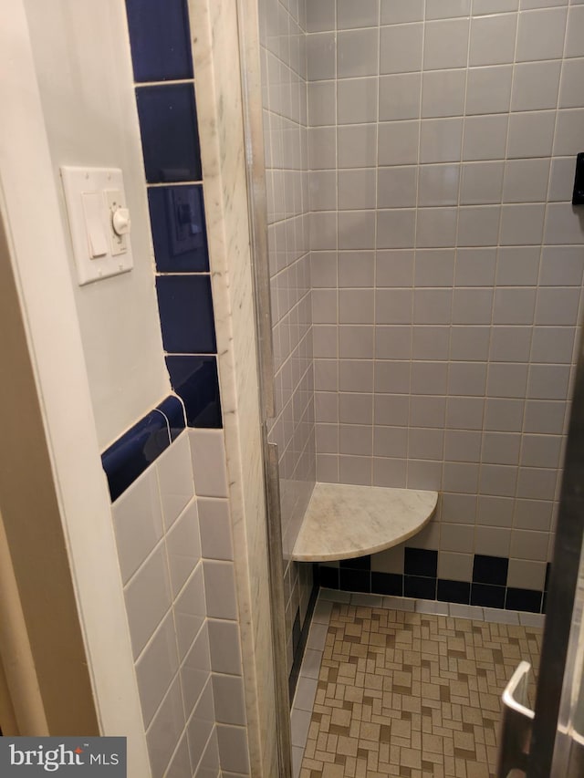 full bathroom with a tile shower and tile walls