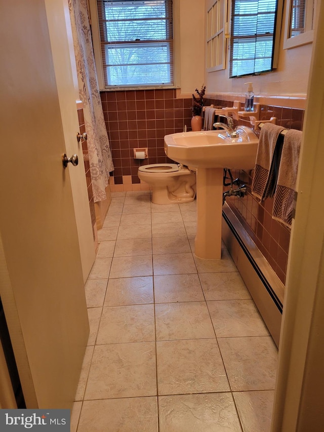 full bathroom featuring toilet, a wainscoted wall, curtained shower, tile patterned flooring, and tile walls