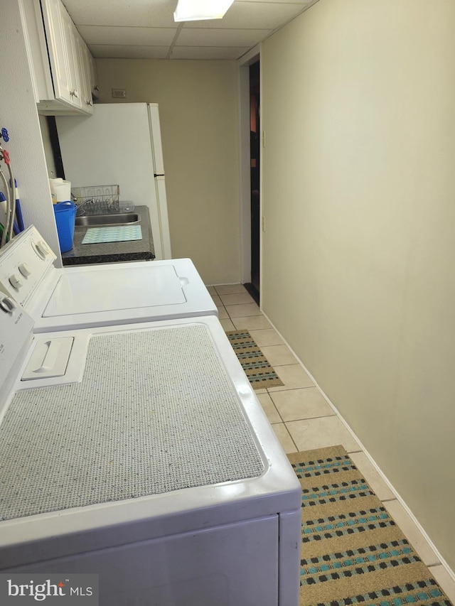 laundry room featuring cabinet space, washing machine and dryer, baseboards, and light tile patterned flooring