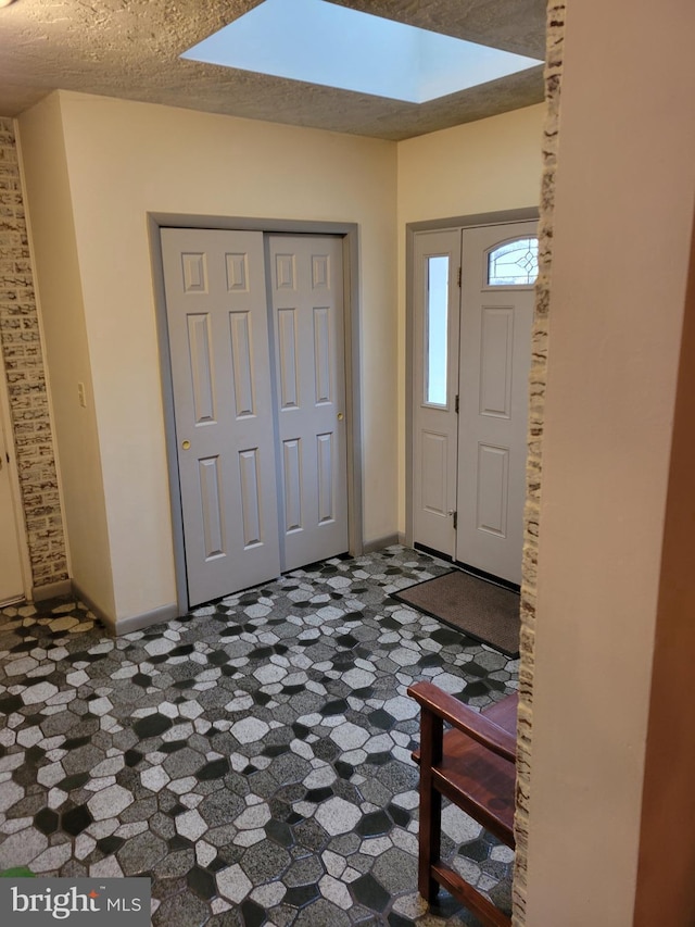 entrance foyer featuring a skylight, baseboards, and a textured ceiling