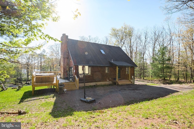 back of property featuring a deck, a yard, and a chimney